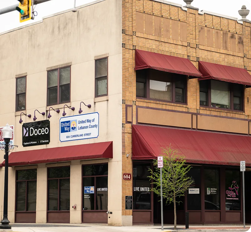 Docco storefront with red awnings at urban corner, clean sidewalk, and traffic light.