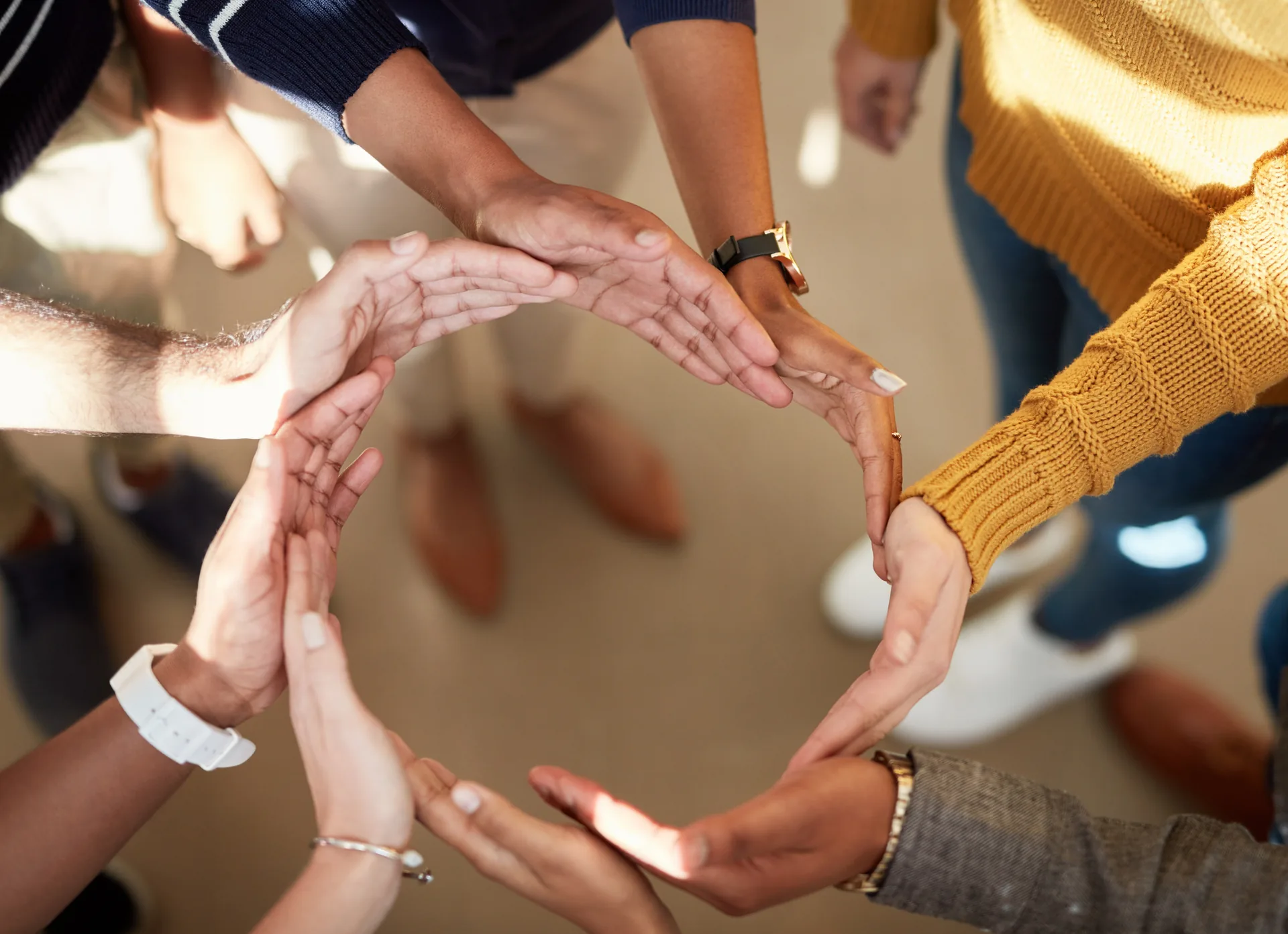 Hands joined in circle, symbolizing unity, community, and shared support.