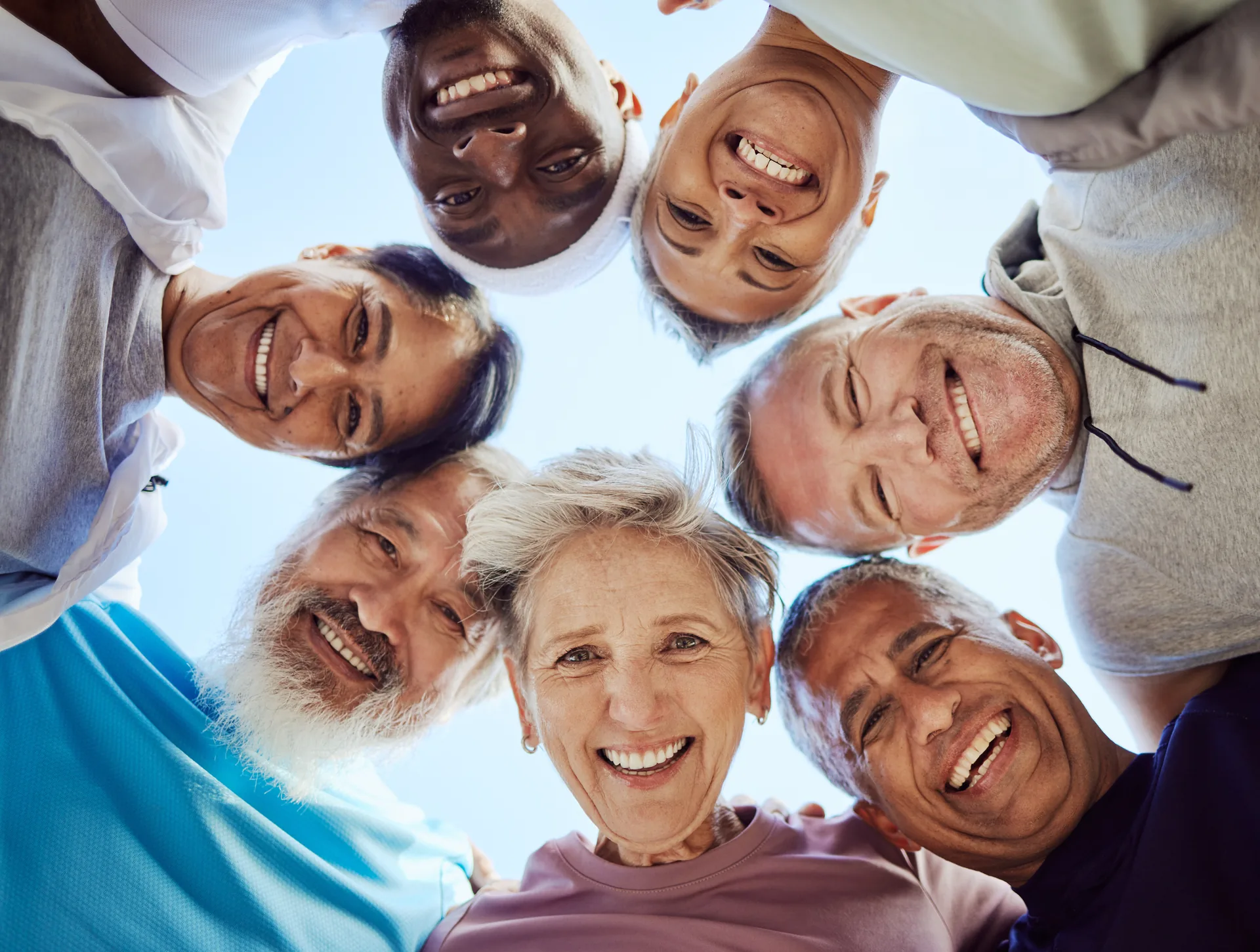 Seven joyful friends in a circle, smiling down from above in bright, happy unity.