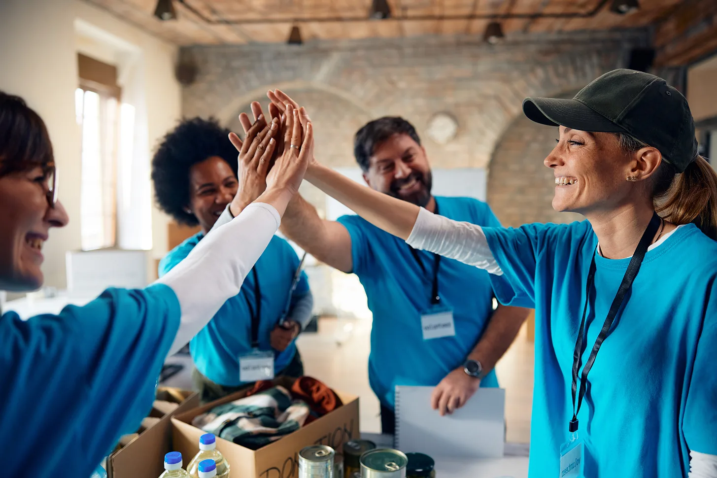 Team celebrates success with joyful high-five at community service event.