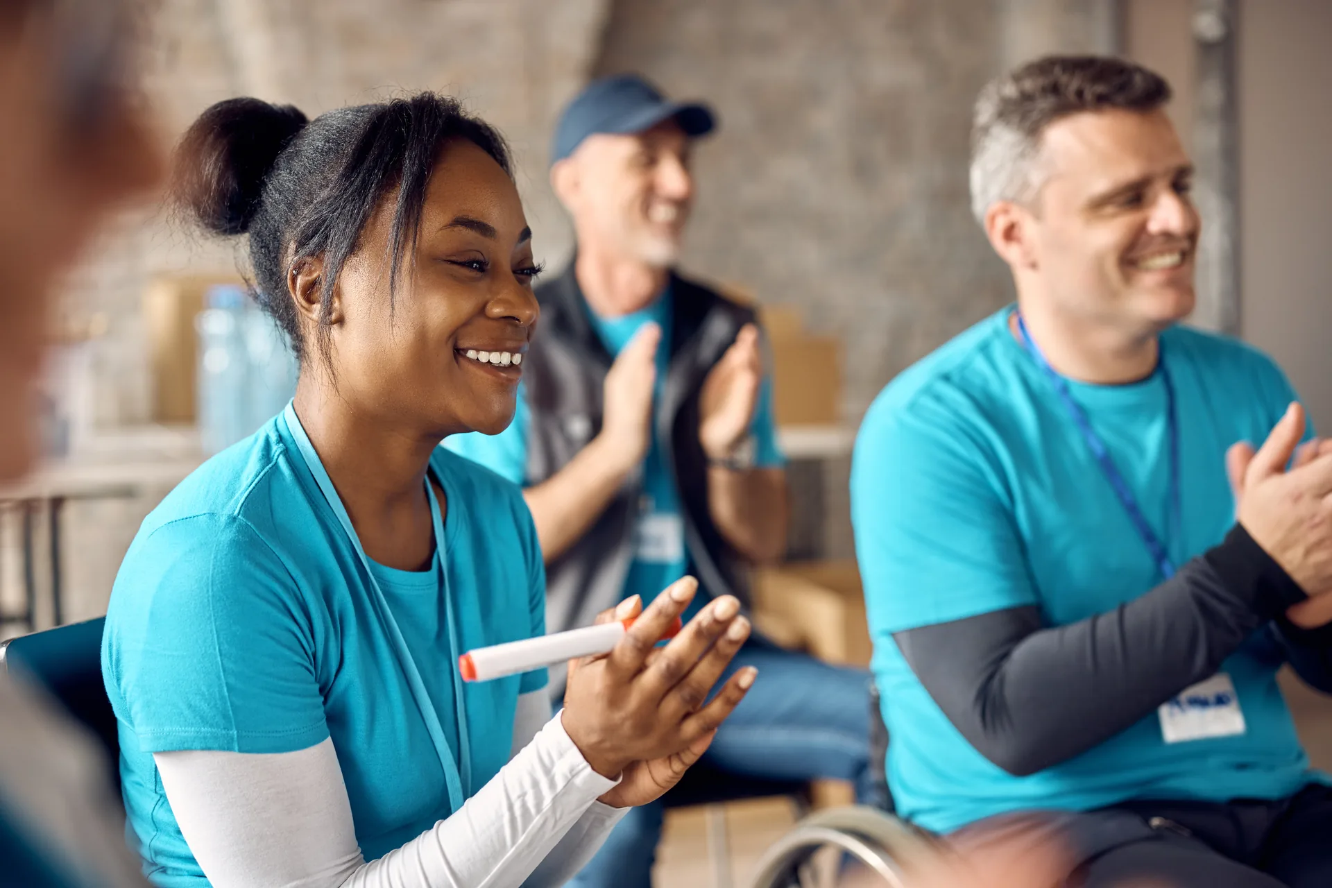 Joyful Black woman clapping with team during lively indoor activity.