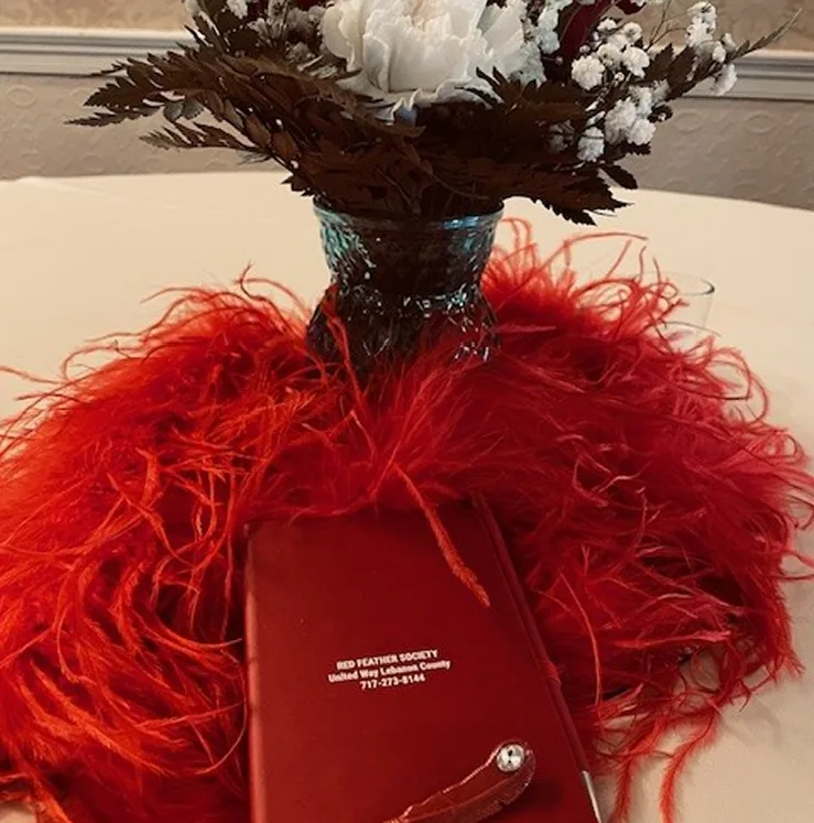 Red feather base with dark vase and white flowers for elegant event decor.