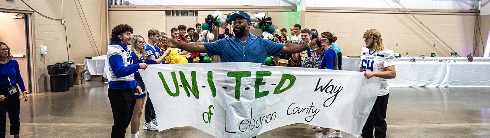 Group holding “United & Coggin County” banner at school event.
