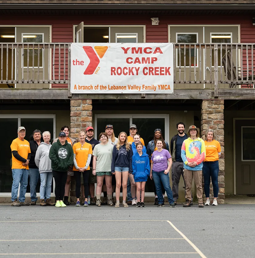 Group photo at YMCA Camp Rocky Creek, smiling campers and staff in front of rustic lodge.